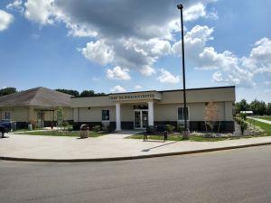 The front of the Poplar Bluff Job Center. It is a flat, wide beige building with two bright white columns on either side of the doorway.