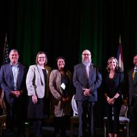 Seven panelists pose on stage for a photo during the 2022 Apprenticeship Summit.